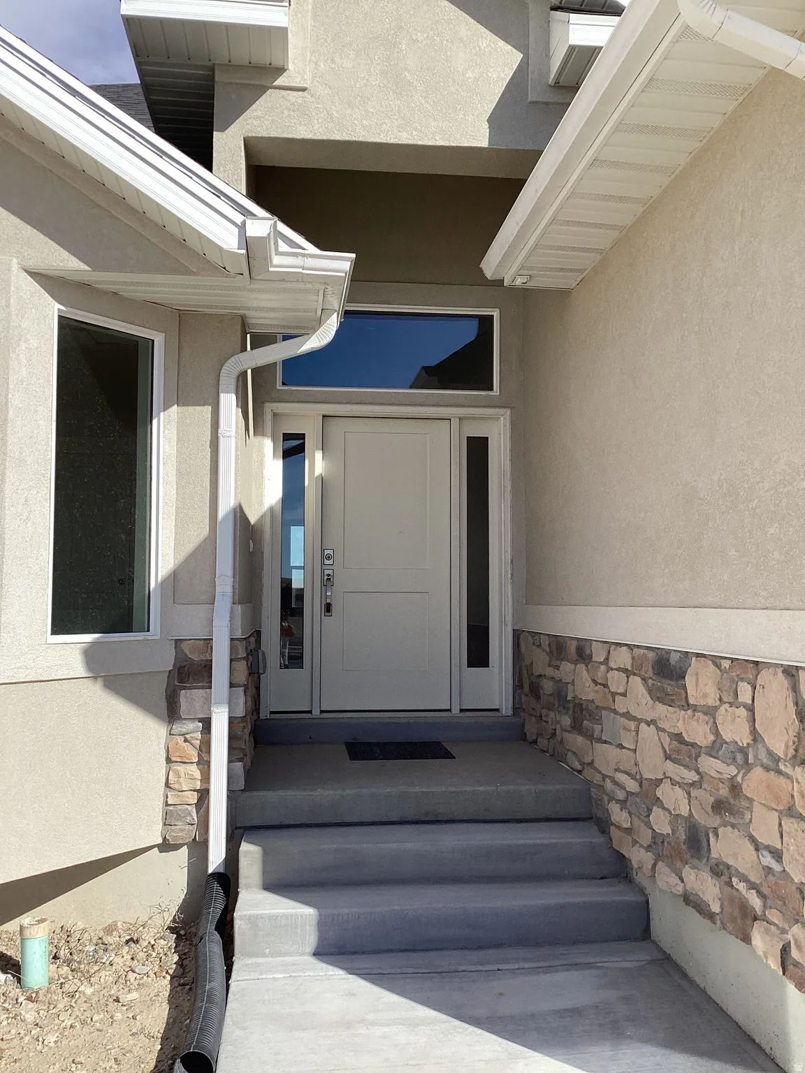 View of exterior entry featuring stone siding and stucco siding