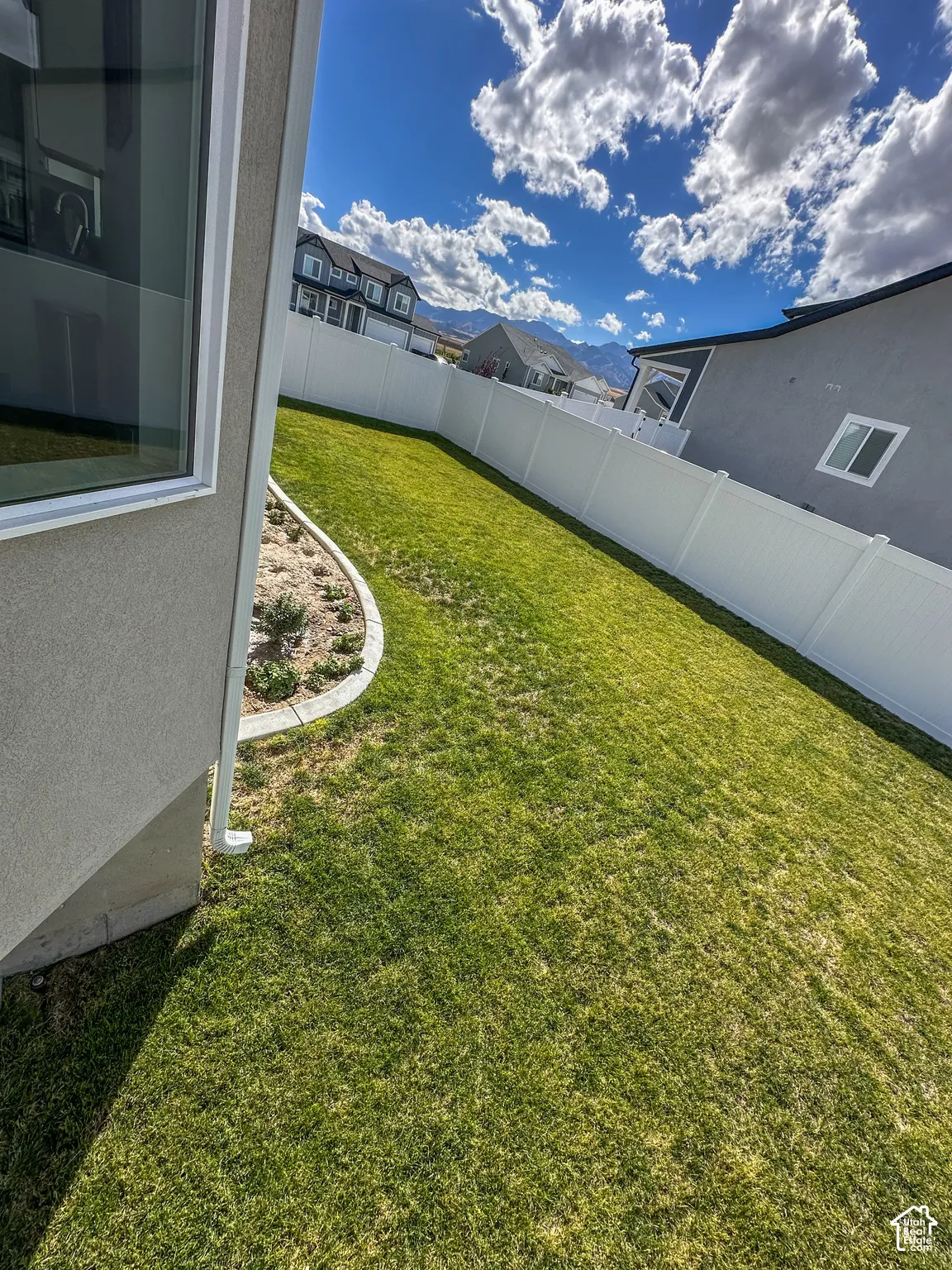 Expansive lawn area with a white privacy fence and curved landscape edging