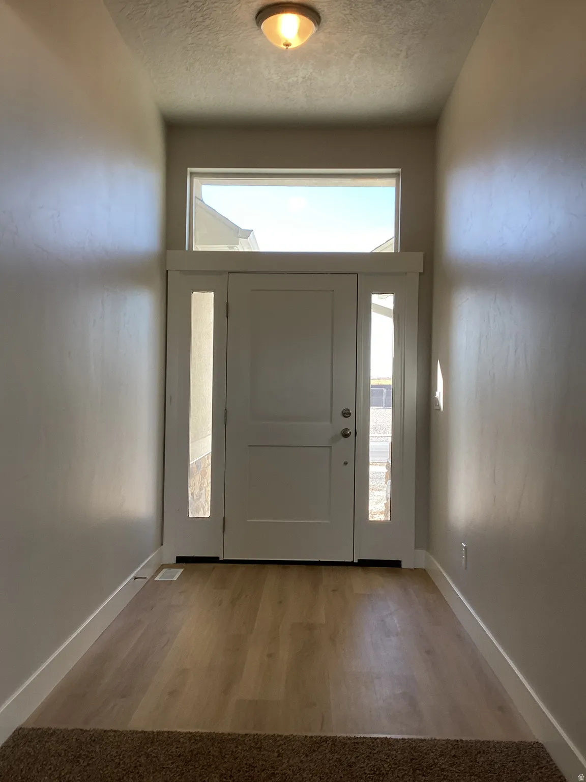 Entryway with light wood-style floors, healthy amount of natural light, and a textured ceiling