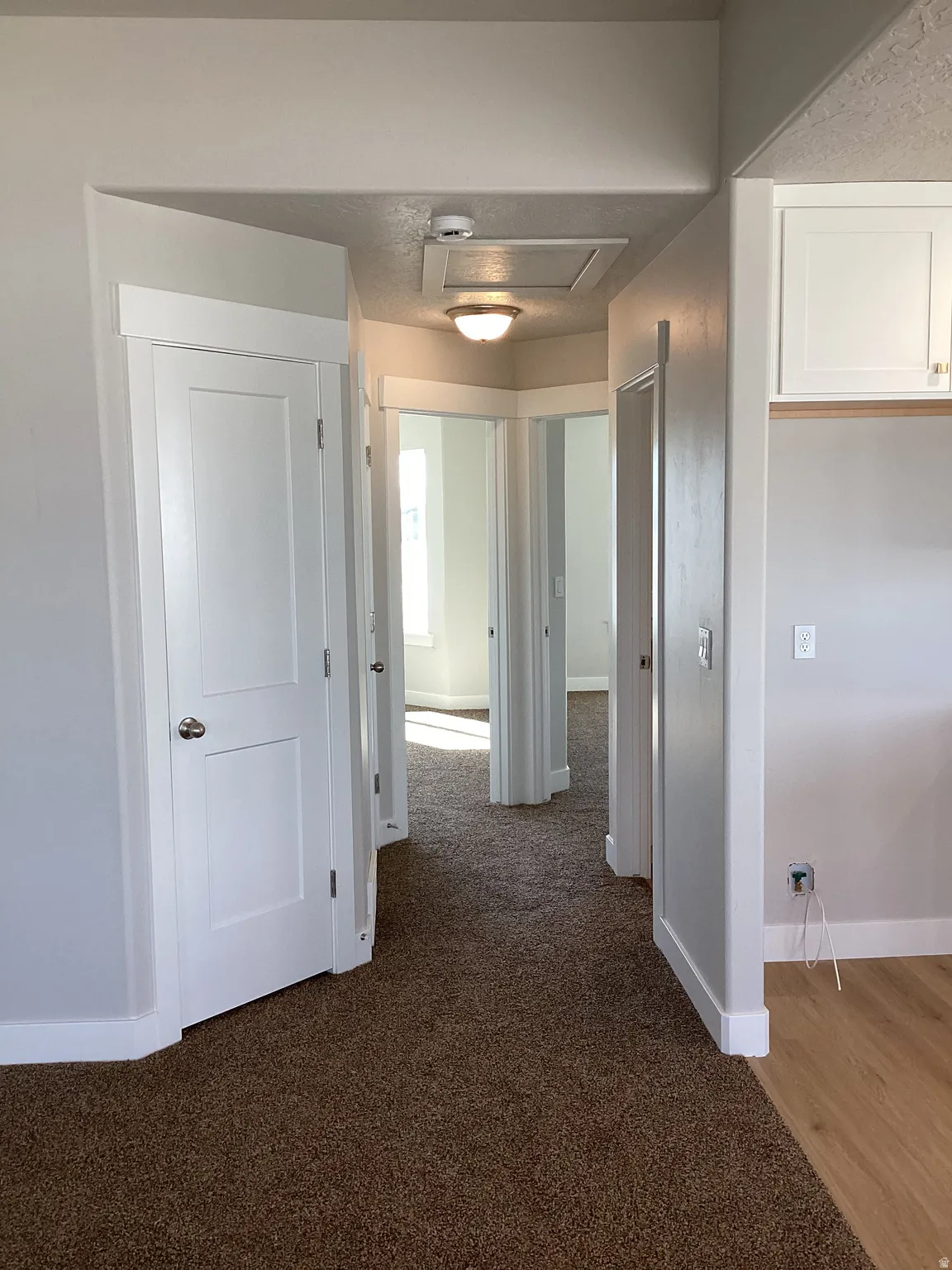 Corridor featuring baseboards and dark colored carpet