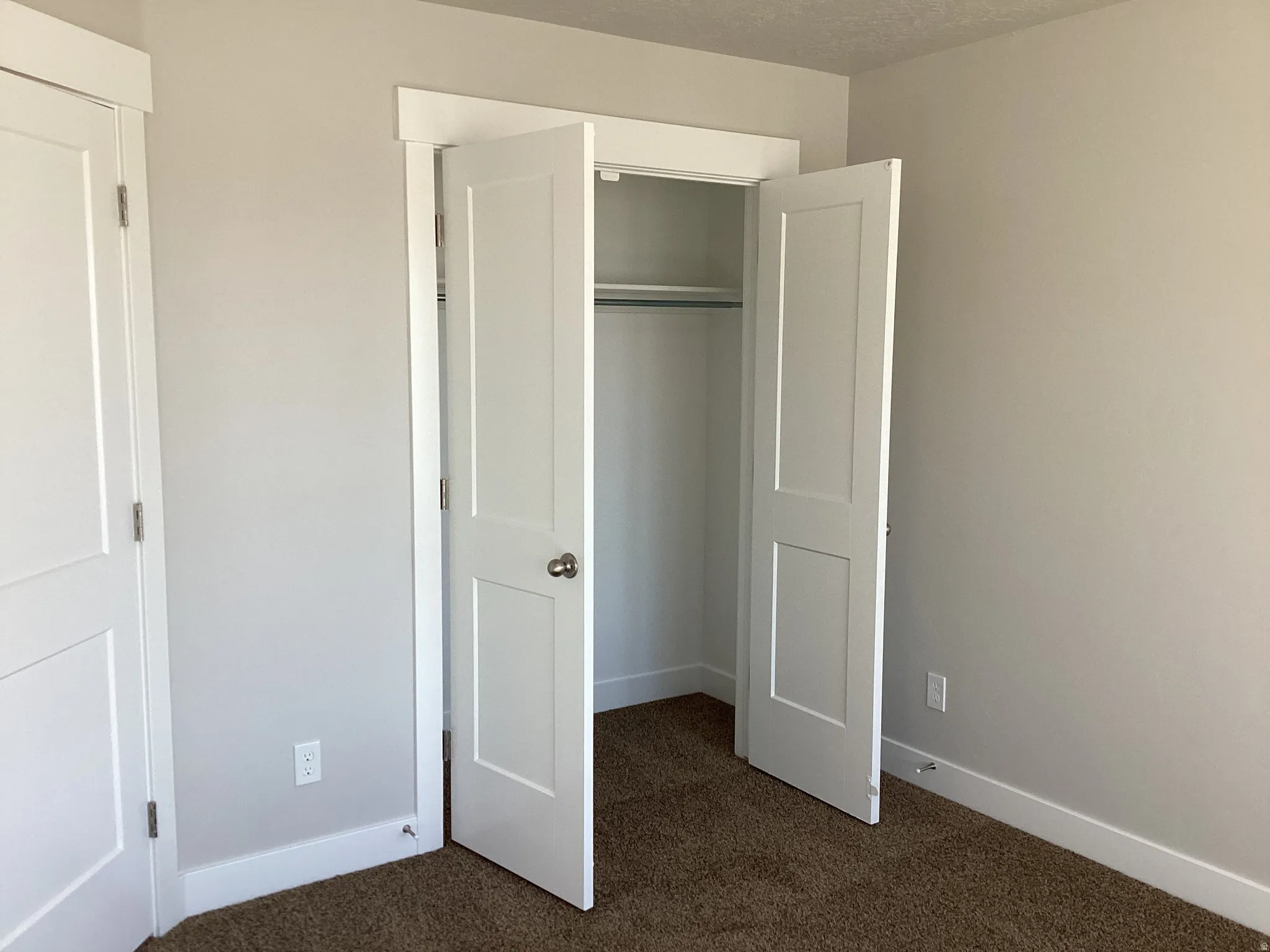 Unfurnished bedroom featuring dark carpet, a closet, and a textured ceiling