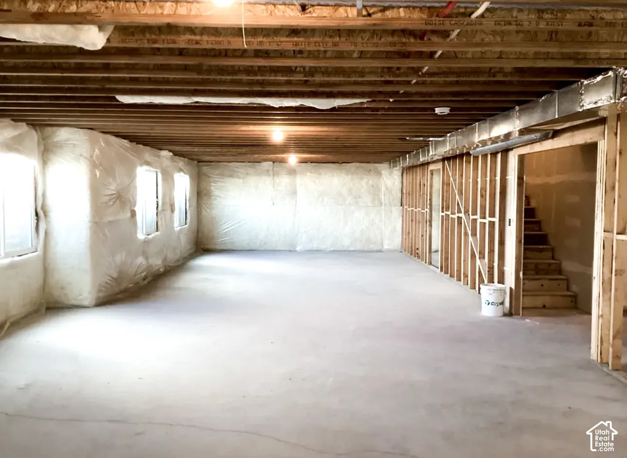 Unfinished lower level featuring exposed wood joists, concrete flooring, multiple windows, and partial wood framing