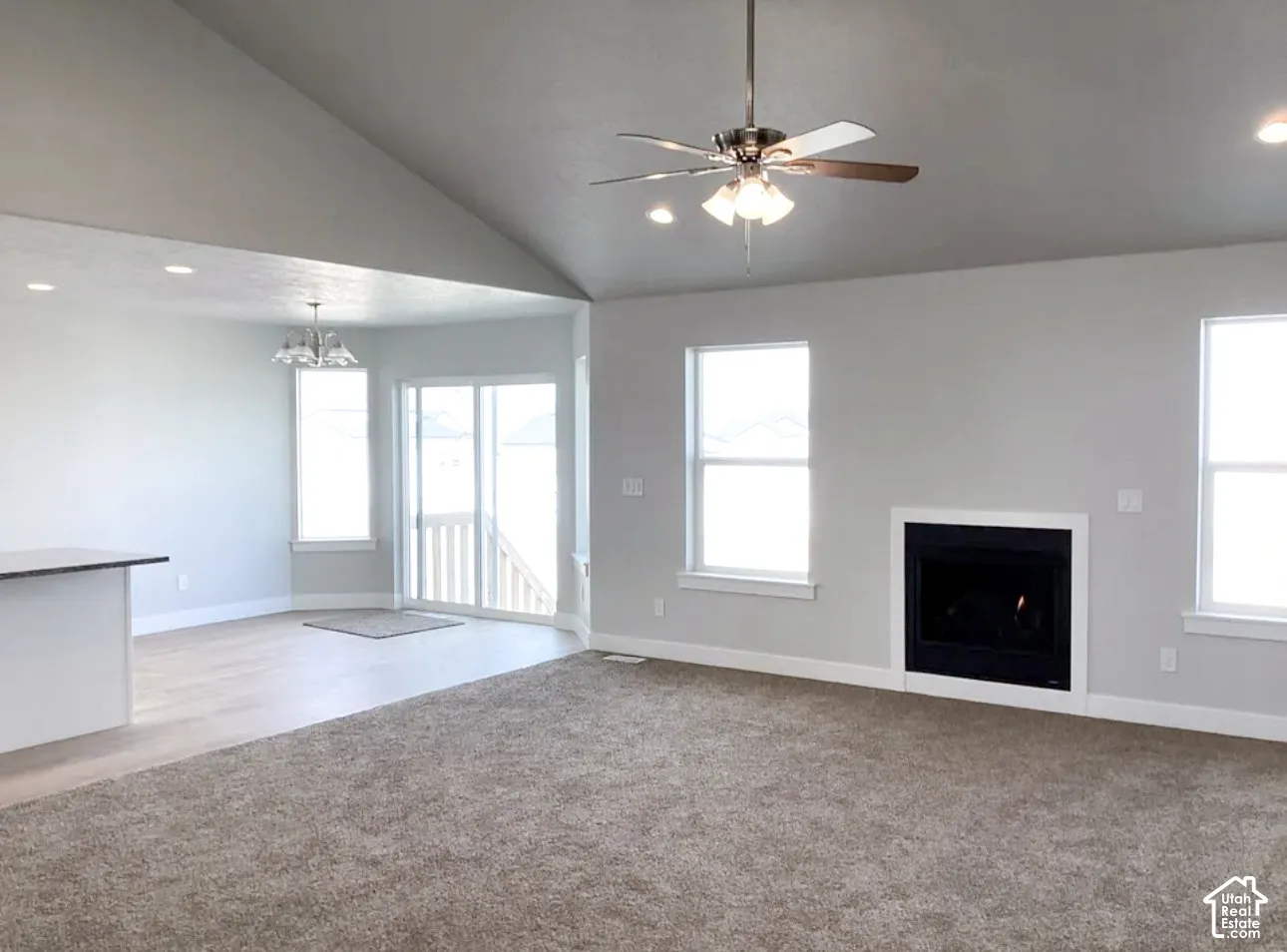 Vaulted ceiling, ceiling fan with integrated lighting, built-in fireplace, recessed lighting, and wood-finish flooring