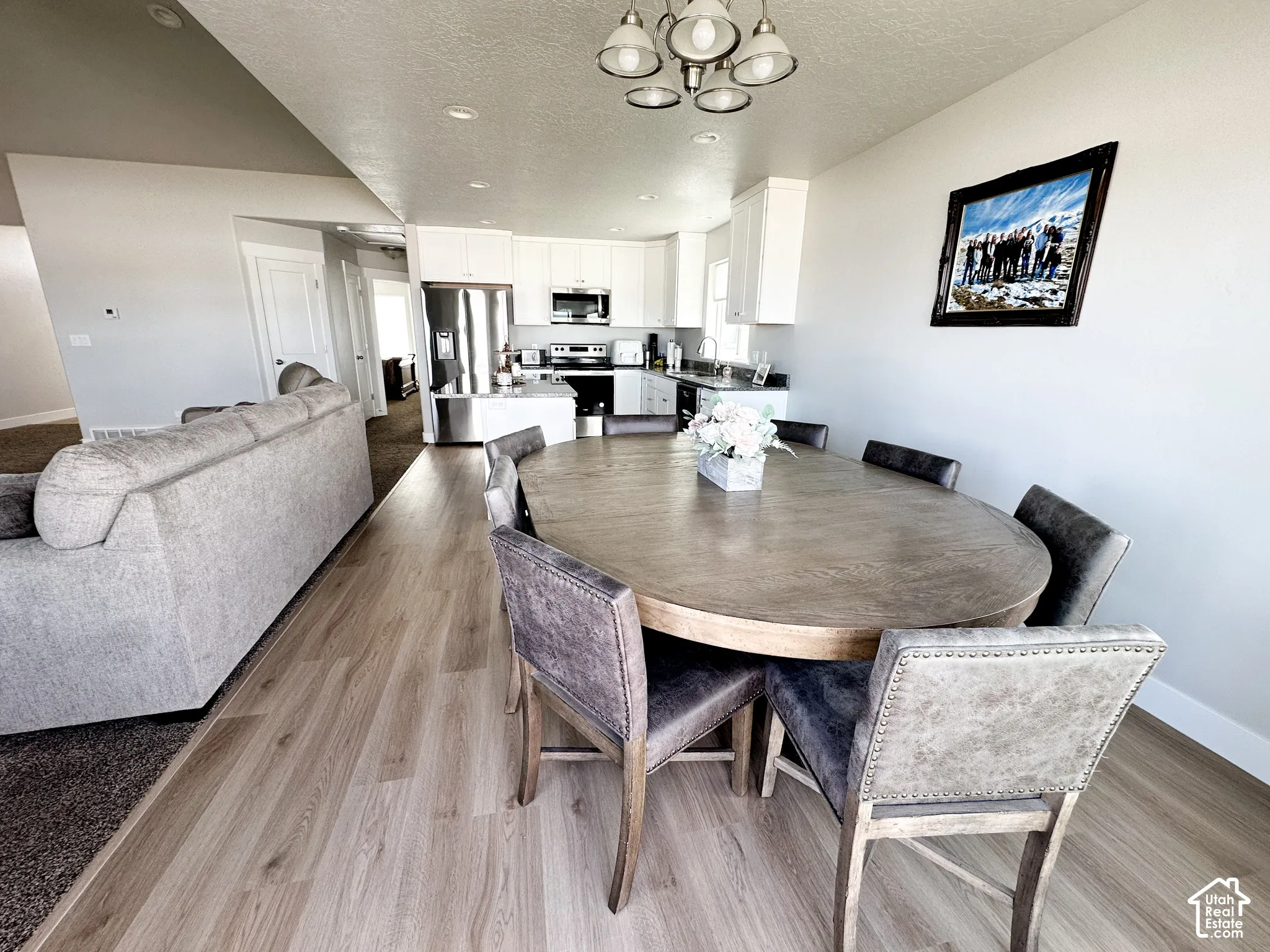 Open-concept living area featuring wood-finish flooring, recessed lighting, and a modern chandelier
