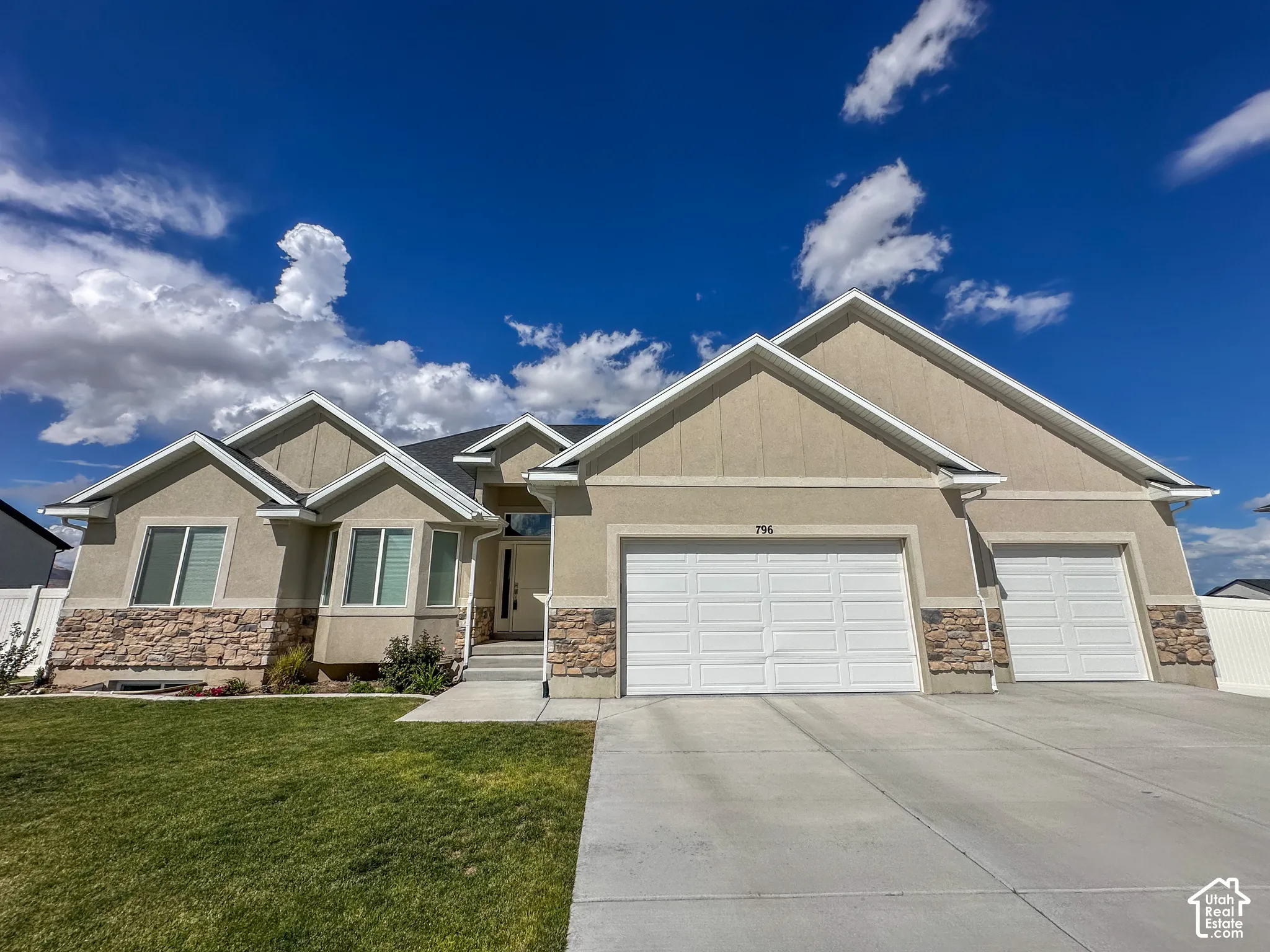 Contemporary facade featuring stone accents, stucco finish, and a concrete driveway