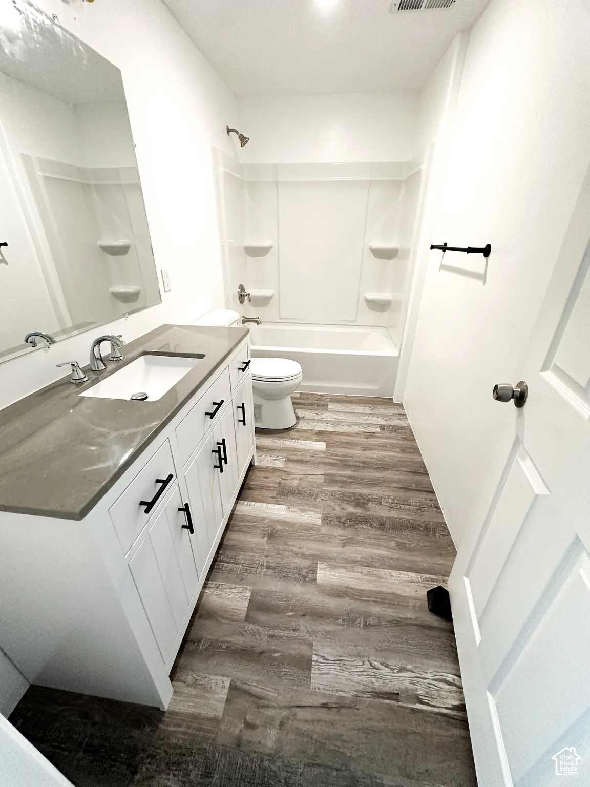 White vanity with dark hardware, undermount sink, and solid surface countertop