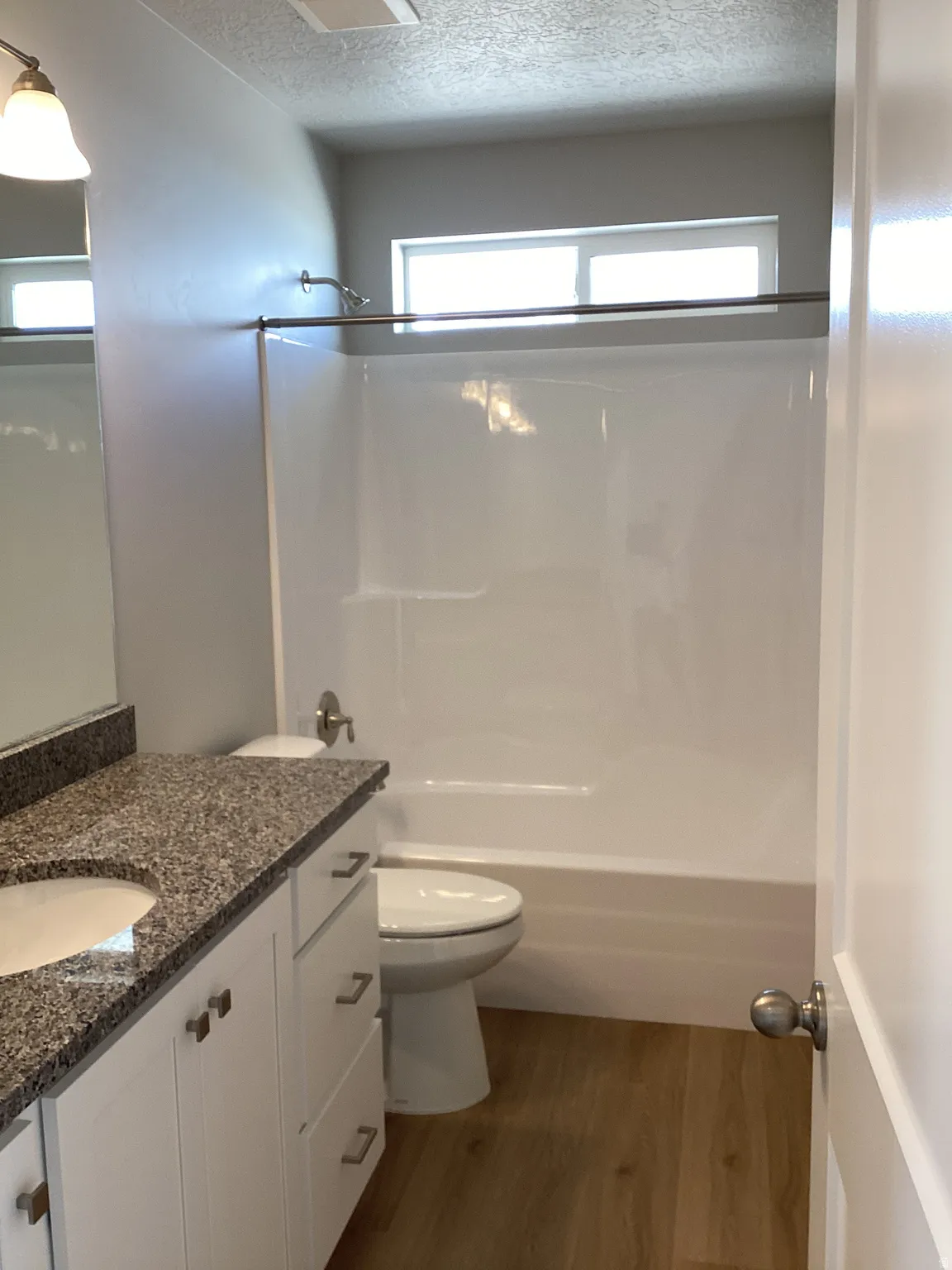 Full bathroom with vanity, dark wood-style floors, a textured ceiling, and shower / bath combination