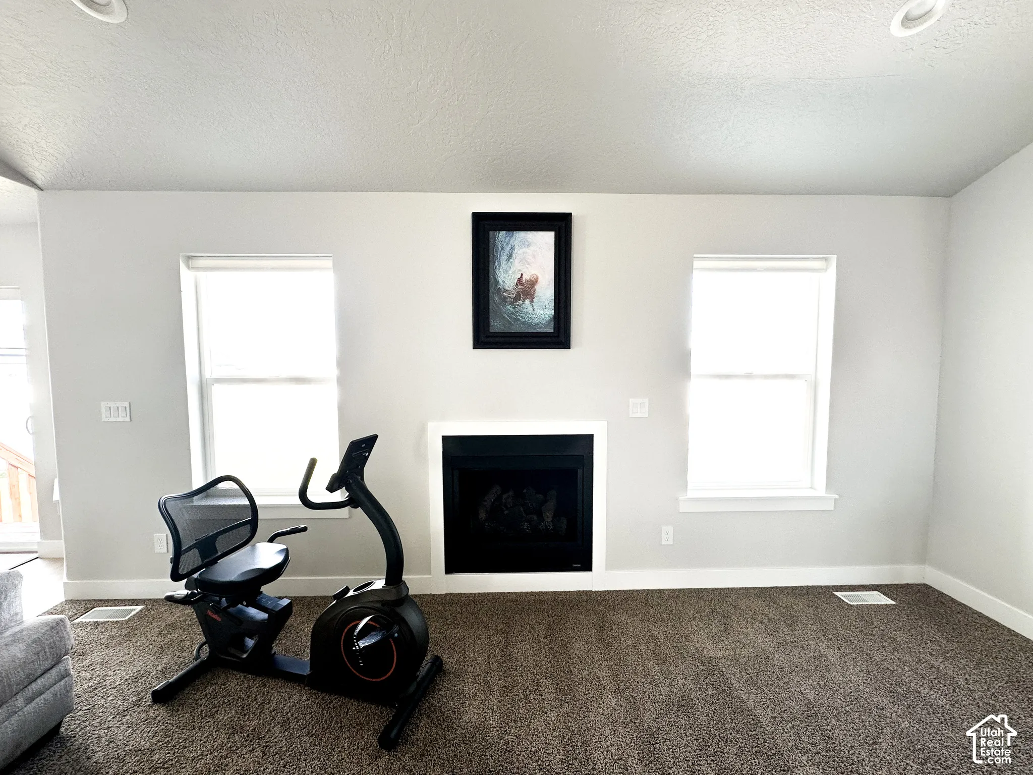 Recessed lighting, light-toned walls, and a fireplace with a white mantel