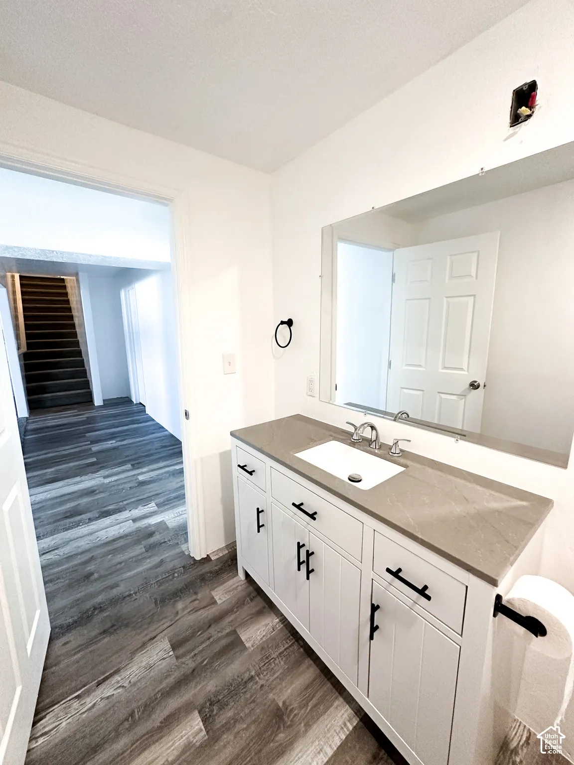 White vanity with black hardware, rectangular undermount sink, and stone-finish countertop