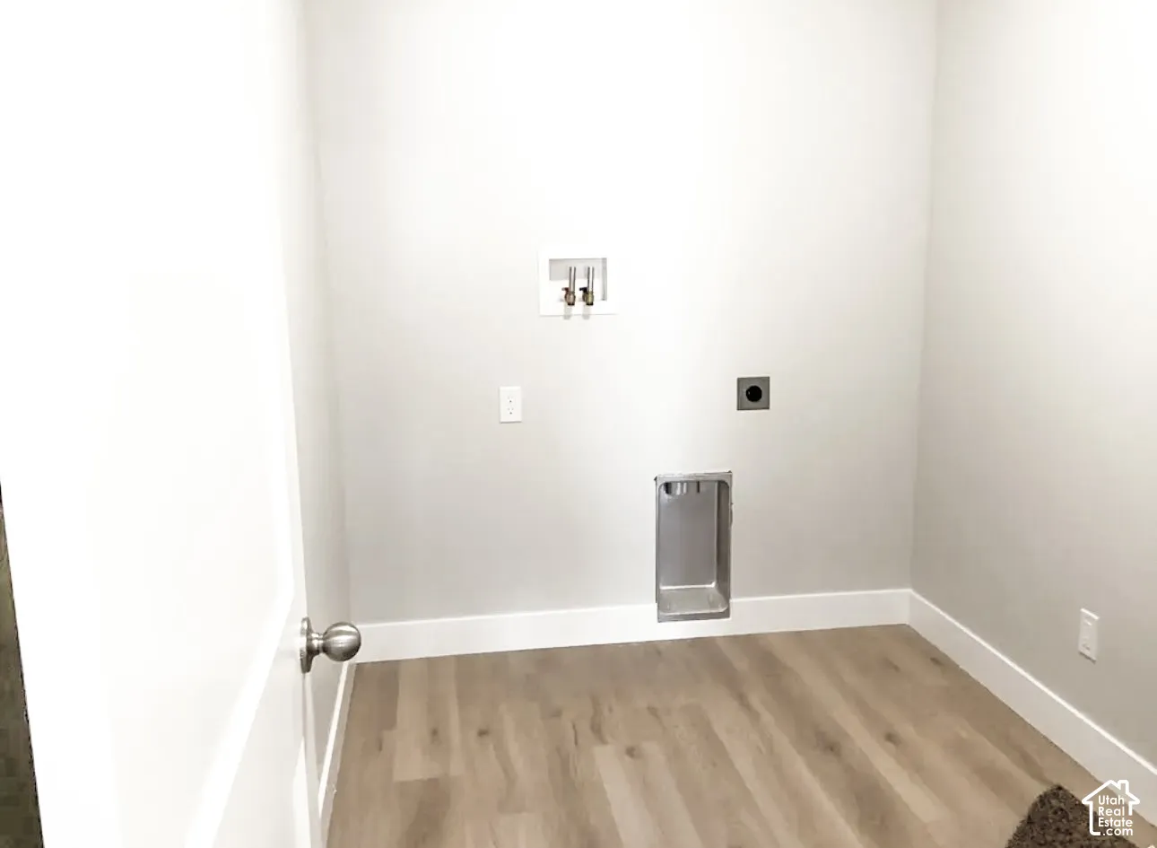 Utility area featuring wood-finish flooring, light neutral wall paint, and white trim
