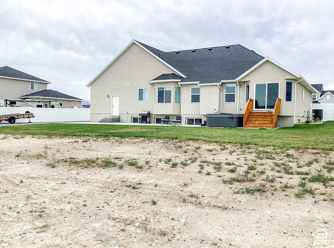 Rear exterior with stucco finish and a dark shingle roof