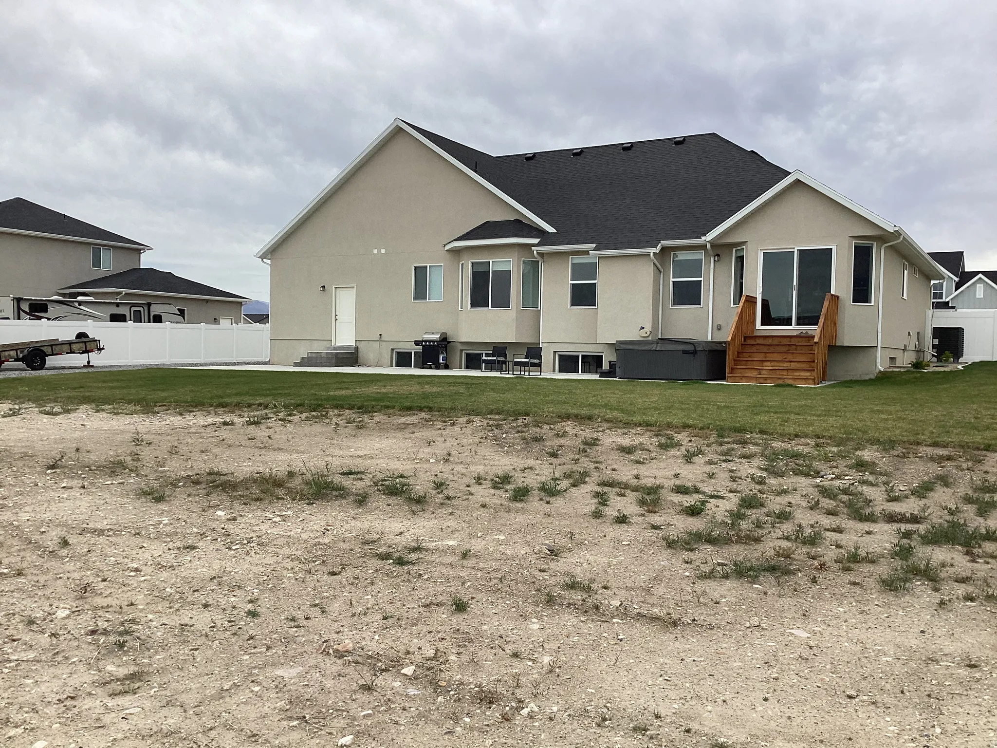 Rear view of house with stucco siding, a patio area, and a shingled roof