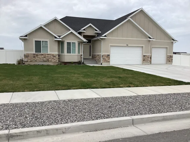 Craftsman-style home with driveway, an attached garage, stone siding, and stucco siding
