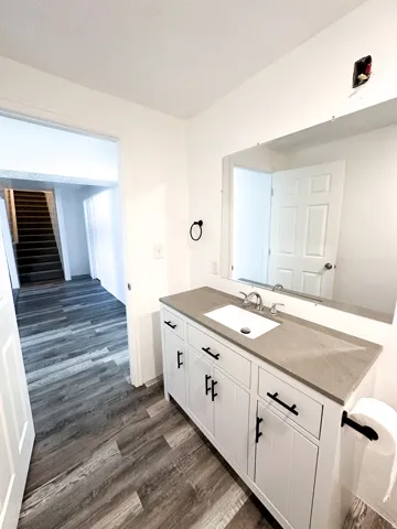 White vanity with black hardware, rectangular undermount sink, and stone-finish countertop