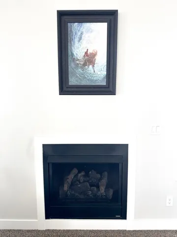 Built-in fireplace with a white surround and a dark metal insert, featuring faux log elements
