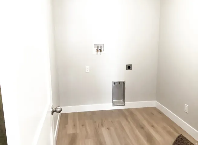 Utility area featuring wood-finish flooring, light neutral wall paint, and white trim