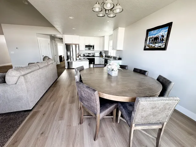 Open-concept living area featuring wood-finish flooring, recessed lighting, and a modern chandelier