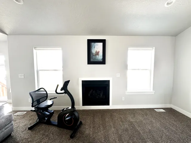 Recessed lighting, light-toned walls, and a fireplace with a white mantel