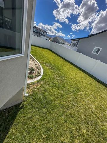 Expansive lawn area with a white privacy fence and curved landscape edging
