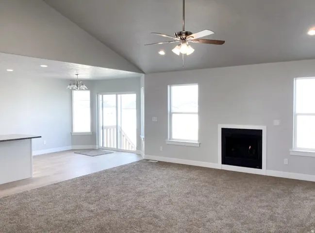 Vaulted ceiling, ceiling fan with integrated lighting, built-in fireplace, recessed lighting, and wood-finish flooring