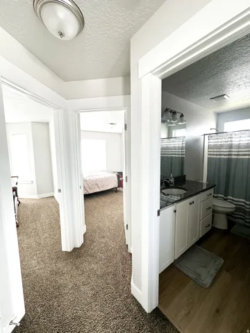 White vanity with dark countertop, undermount sink, and three-light fixture