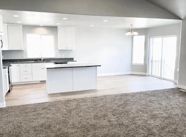 Kitchen featuring white cabinetry, dark countertops, a central island, recessed lighting, and wood-finish flooring