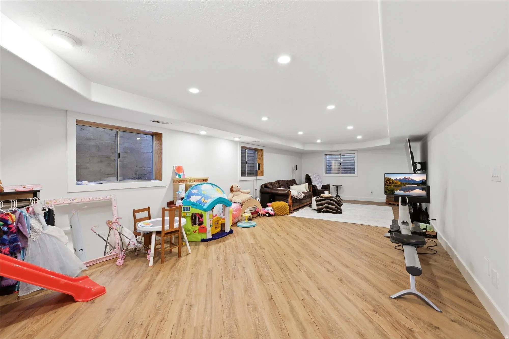 Recreation room with recessed lighting, light wood-style flooring, and a raised ceiling