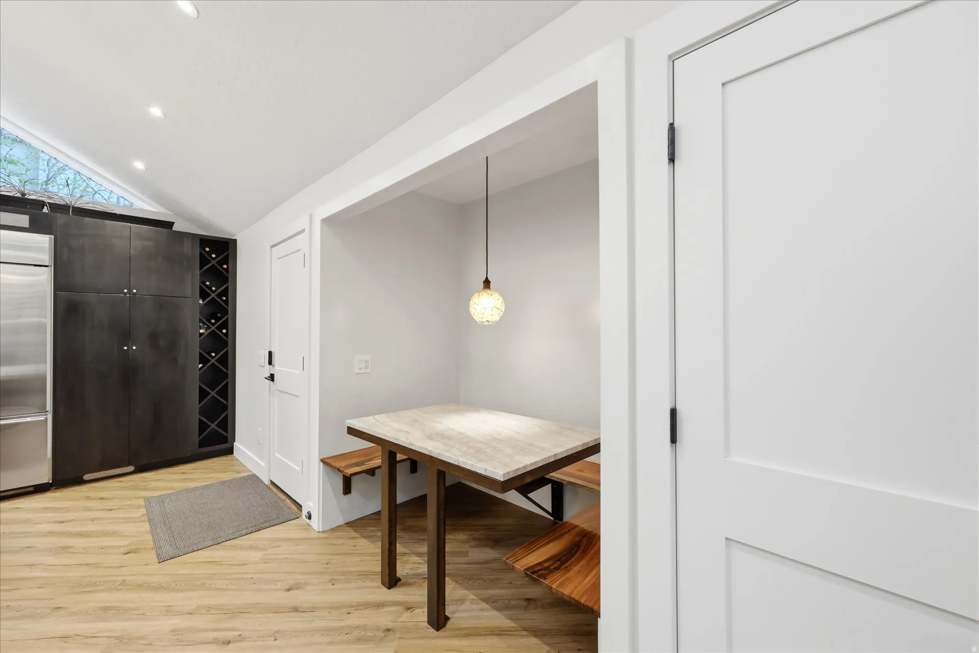 Dining space with light wood-style flooring, vaulted ceiling, and recessed lighting