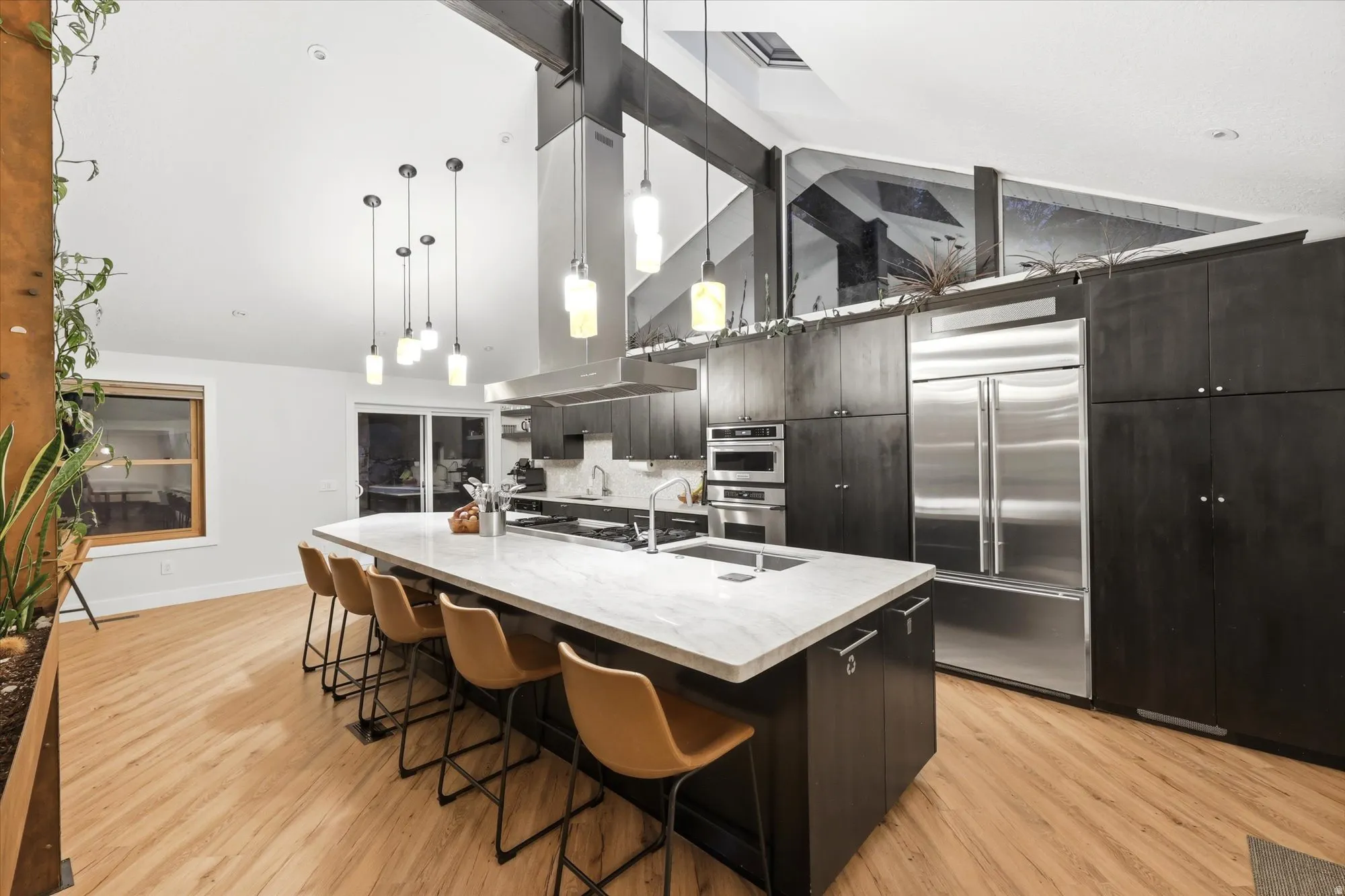 Kitchen with modern cabinets, a breakfast bar area, stainless steel appliances, light wood-style floors, and a large island with sink