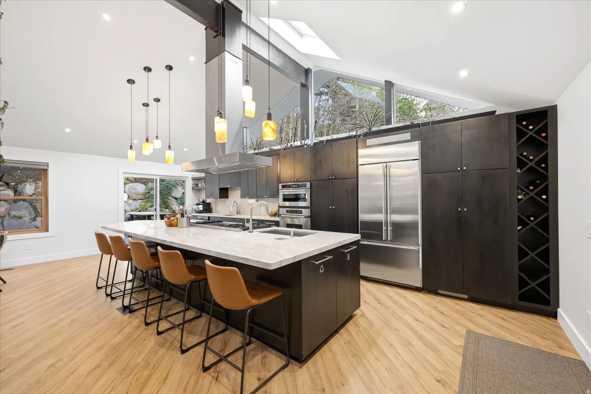 Kitchen with a kitchen bar, modern cabinets, a spacious island, dark wood finish cabinetry, and stainless steel appliances