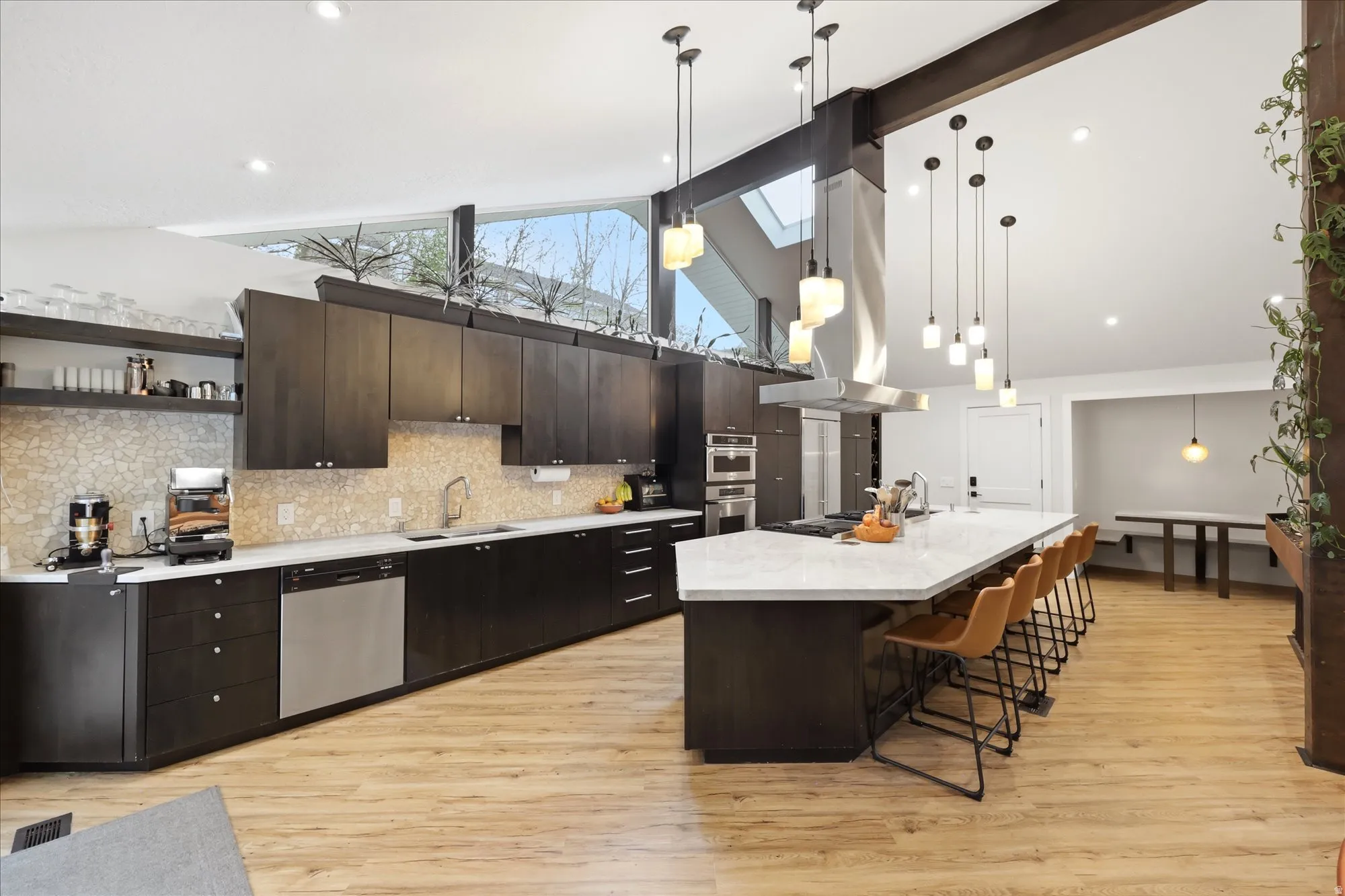 Kitchen featuring dark wood finish cabinetry, a large island, island range hood, a kitchen breakfast bar, and lofted ceiling
