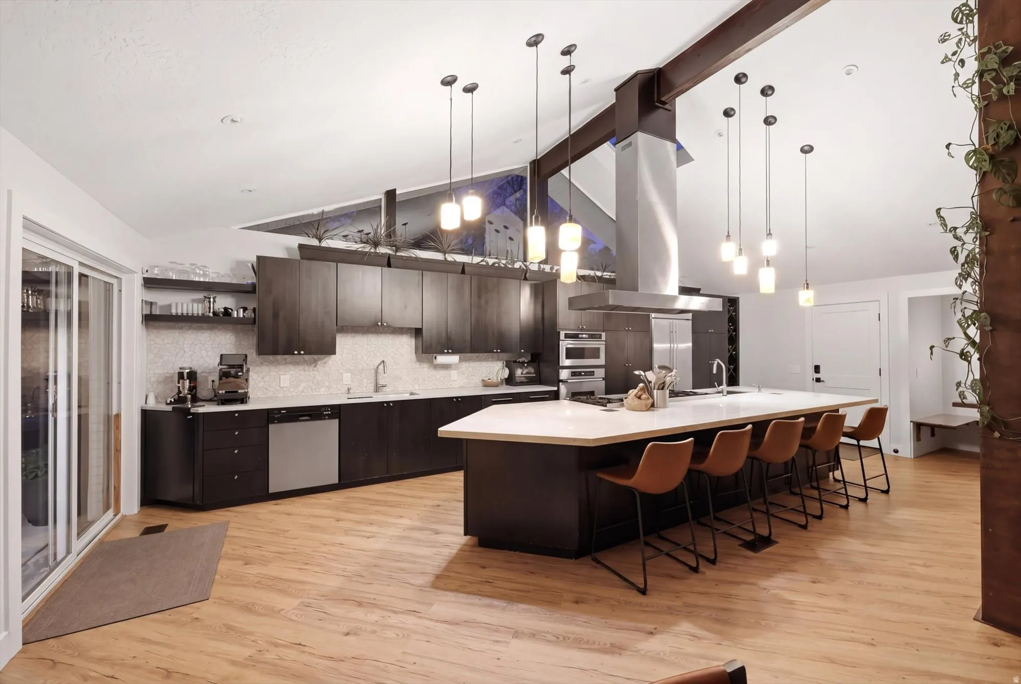 Kitchen with dark wood finish cabinetry, a kitchen bar, a spacious island, island exhaust hood, and stainless steel appliances