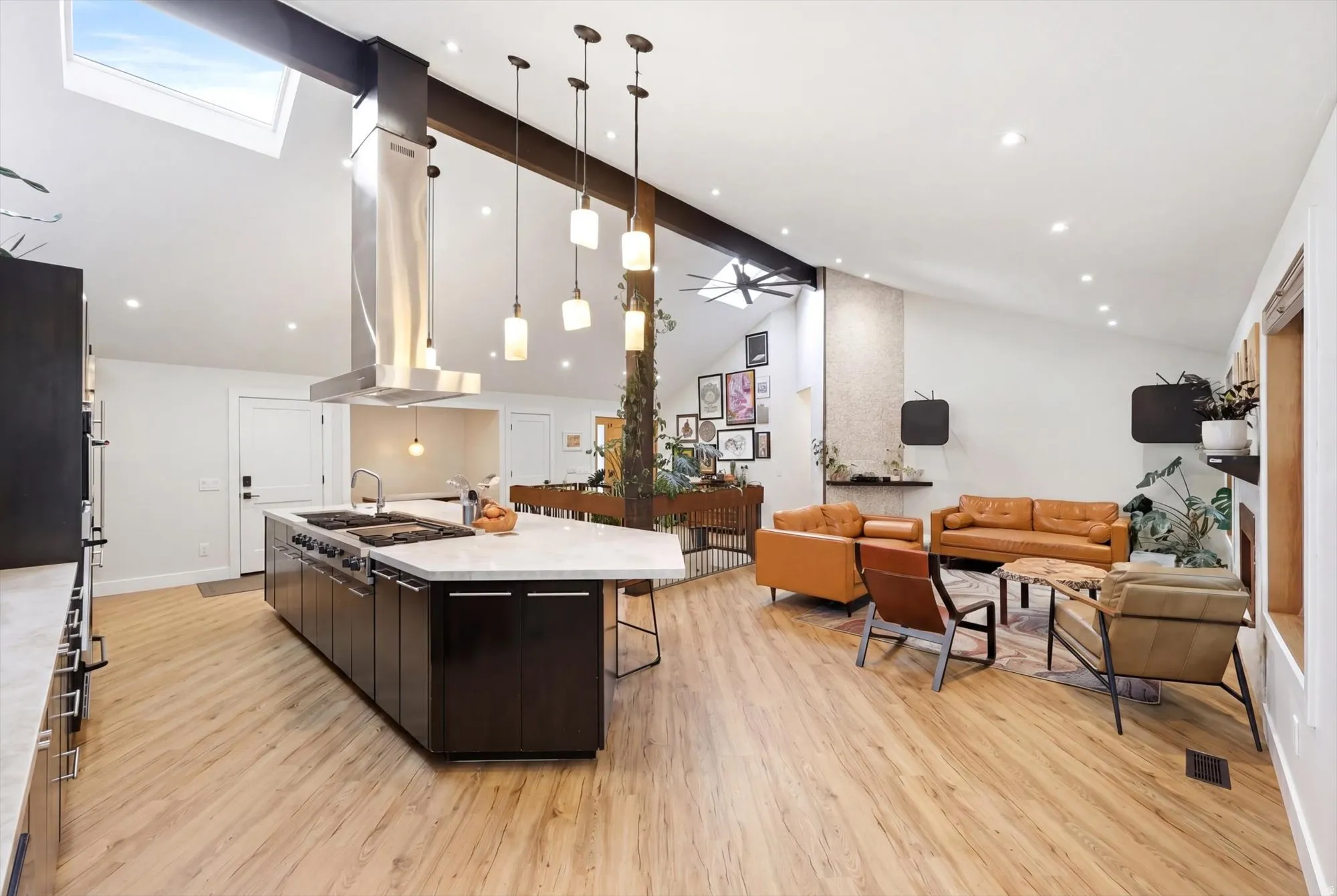 Kitchen featuring open floor plan, pendant lighting, island exhaust hood, light wood-type flooring, and a large island