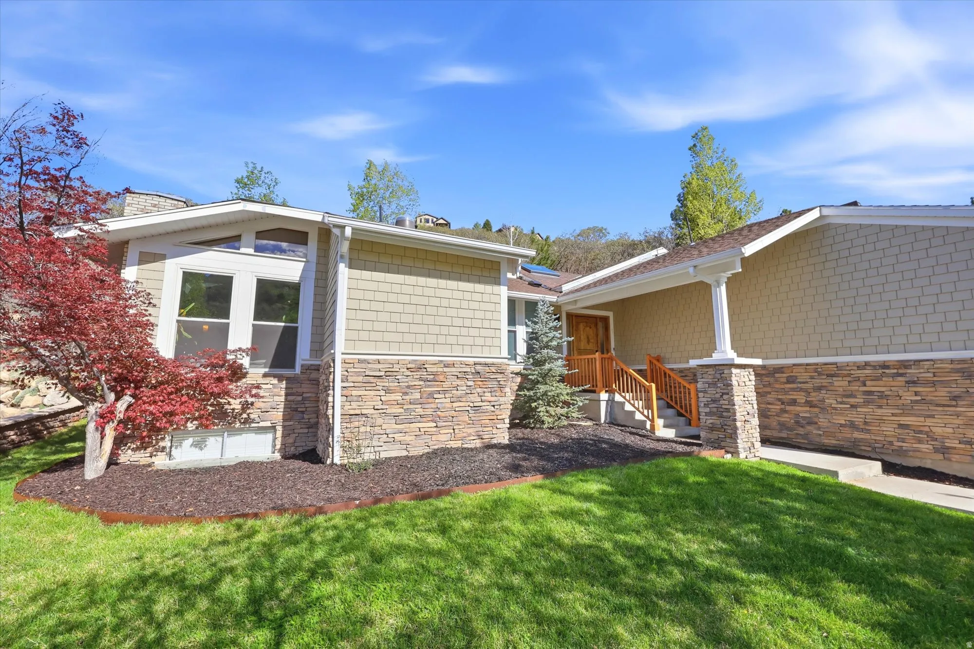 View of front of house featuring stone siding and a front yard