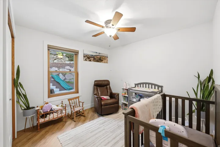 Bedroom with light wood-style flooring, a crib, and a ceiling fan