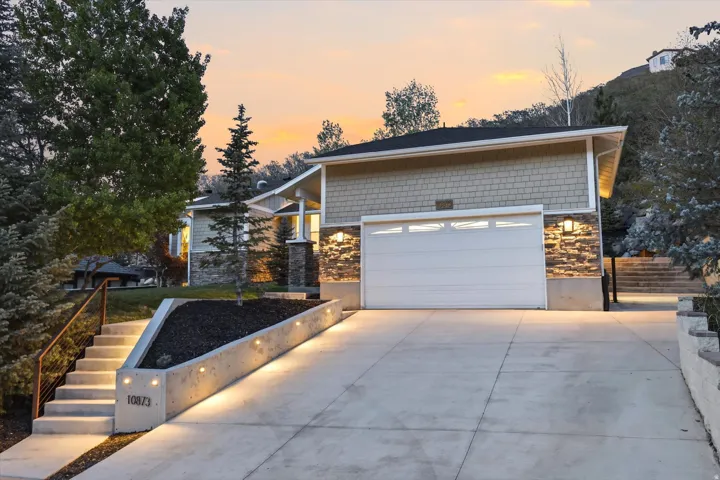 View of front of property with stone siding, concrete driveway, and an attached garage