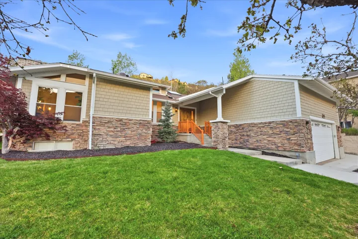 View of front of property featuring stone siding, a front yard, and driveway
