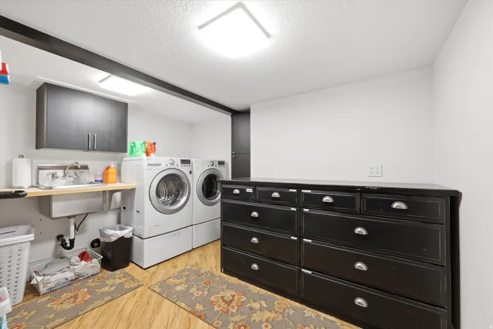 Laundry area featuring cabinet space, a textured ceiling, light wood-style flooring, and independent washer and dryer