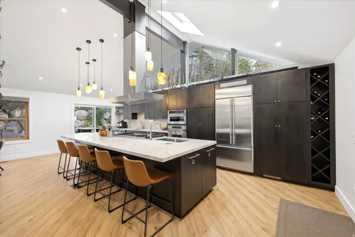 Kitchen with a kitchen bar, modern cabinets, a spacious island, dark wood finish cabinetry, and stainless steel appliances