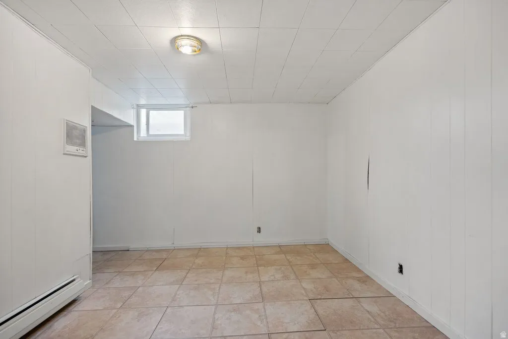 Basement featuring baseboard heating and light tile patterned floors
