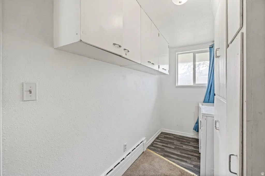 Laundry room featuring a baseboard radiator, washer / clothes dryer, and dark carpet