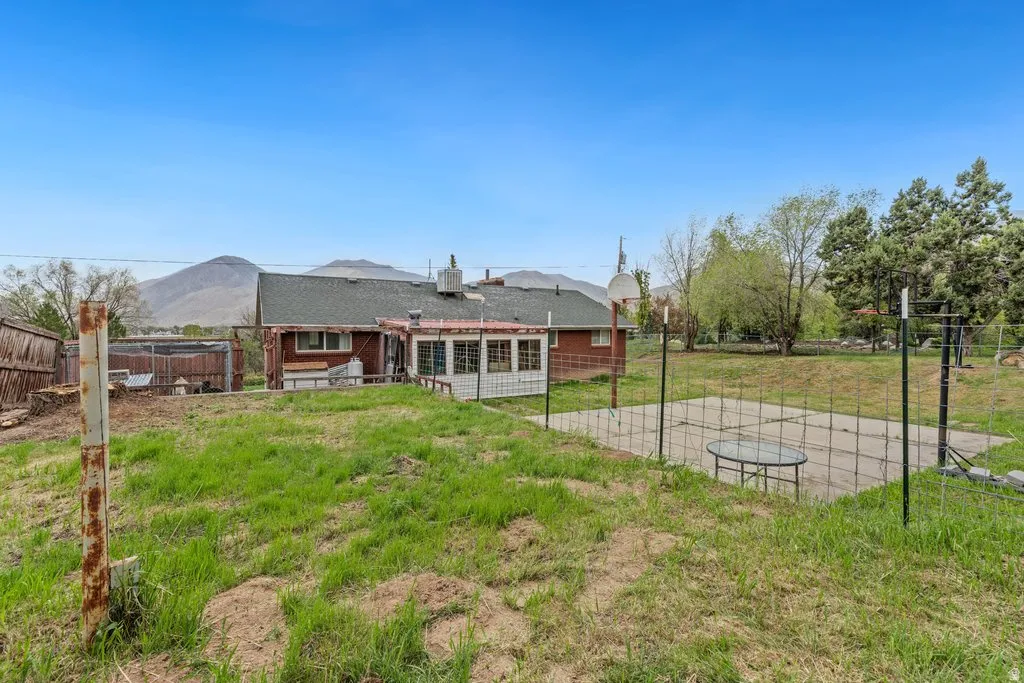 Back of house with a fenced backyard, basketball court, and a patio area