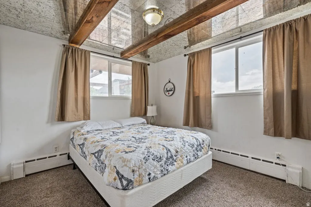 Bedroom featuring baseboard heating and dark carpet