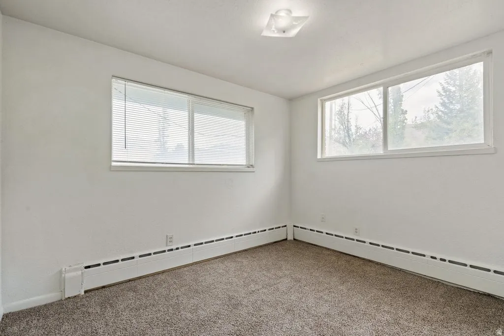 Carpeted empty room with a baseboard radiator
