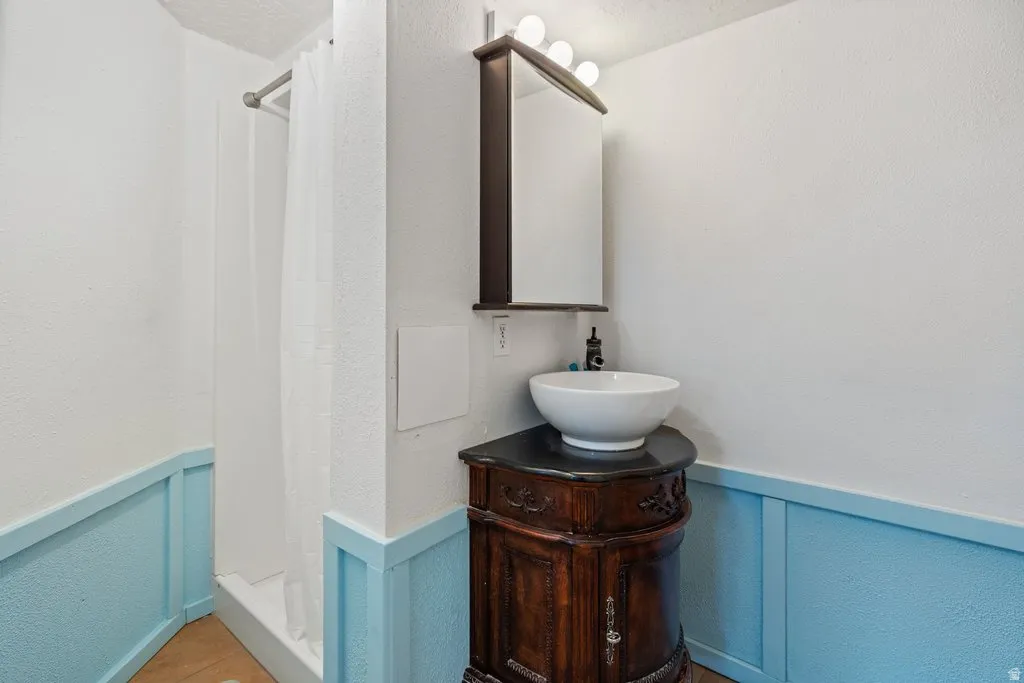 Bathroom with a wainscoted wall, a decorative wall, a stall shower, vanity, and a textured wall