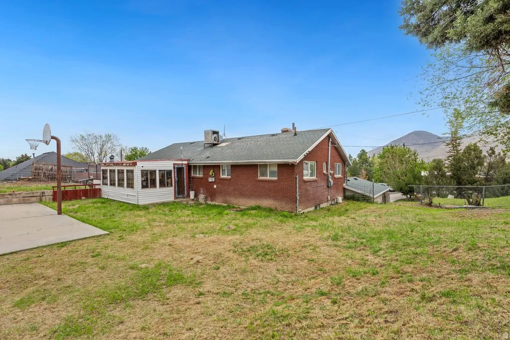 Back of property with a sunroom and brick siding