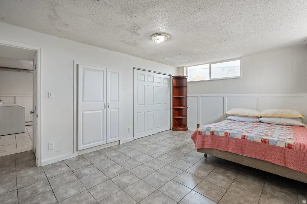 Bedroom featuring a textured ceiling, a decorative wall, washer / dryer, and a closet