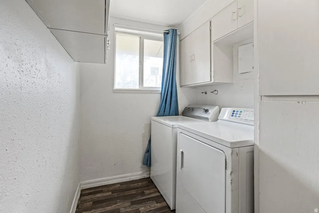 Laundry area with dark wood-style flooring, washing machine and dryer, and a textured wall