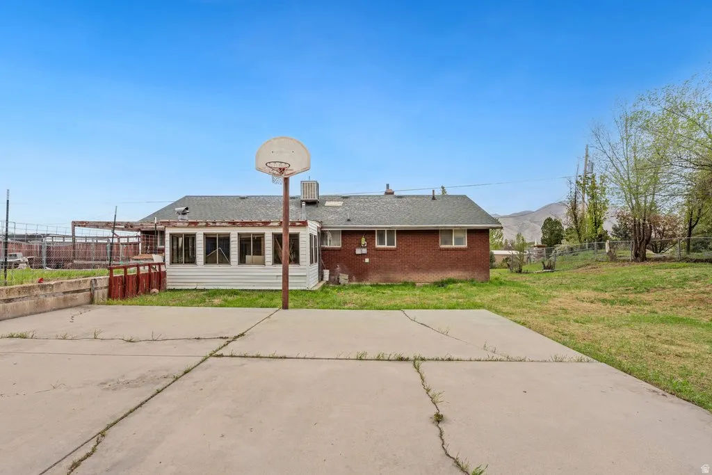 Back of house with brick siding, a patio, a fenced backyard, and roof with shingles