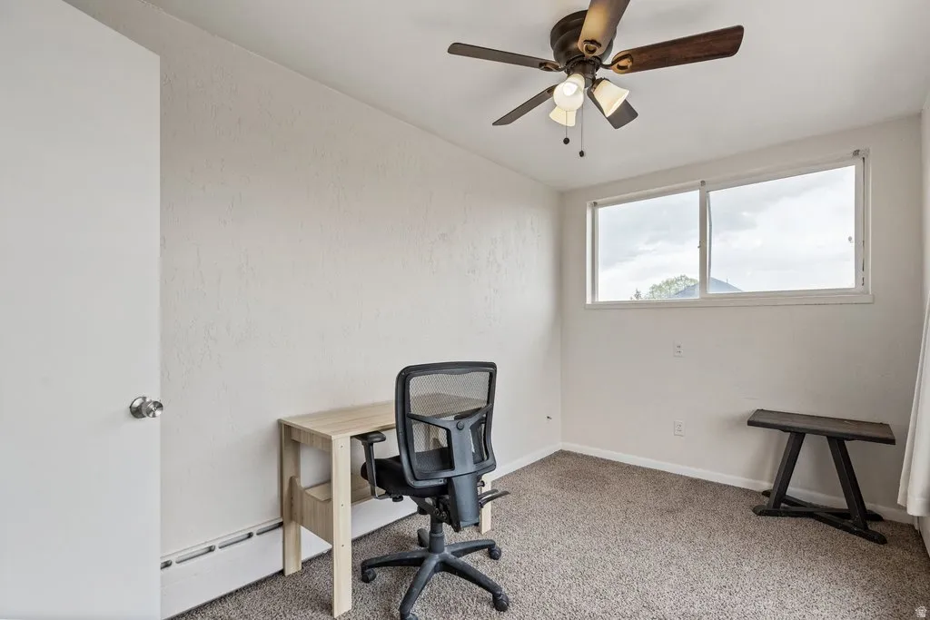 Office space featuring a baseboard heating unit, carpet floors, and ceiling fan